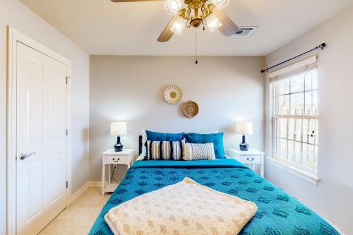 a bedroom with a blue bed and two windows at The Brick Beauty on Cabriolet in Bentonville
