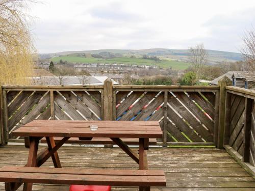 a wooden bench on a wooden deck with a fence at The Bike Shed in Disley