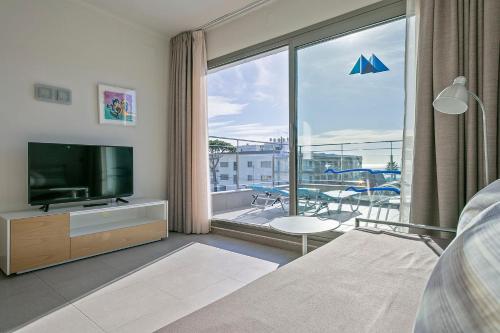 a living room with a television and a balcony at Apartamentos Castellmar in Castelldefels