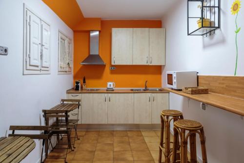 バルセロナにあるモンルームズ バルセロナのオレンジ色の壁と木製のスツールが備わるキッチン