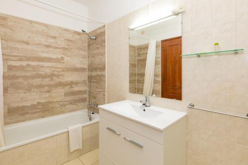 een badkamer met een wastafel, een bad en een spiegel bij Natura Algarve Club in Albufeira