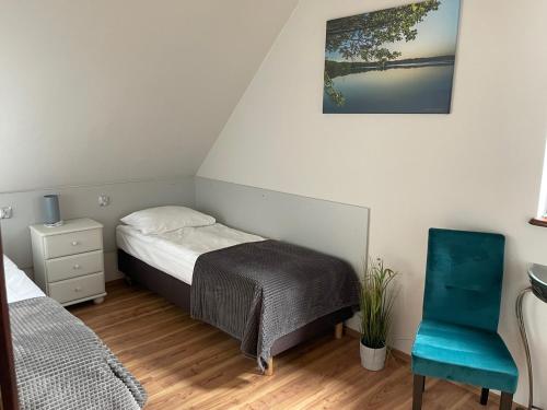 a small bedroom with a bed and a blue chair at Dom Wakacyjny Myśliborka in Nowe Warpno
