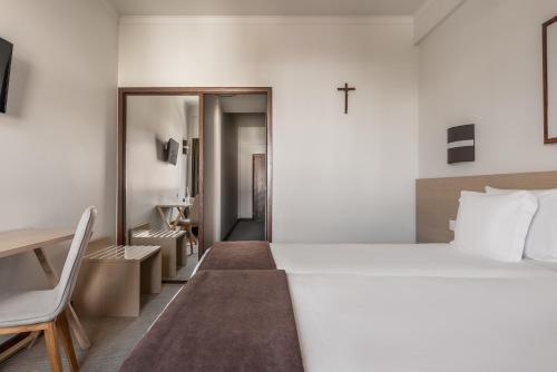a bedroom with a large bed and a cross on the wall at Crisol Tres Pastorinhos in Fátima