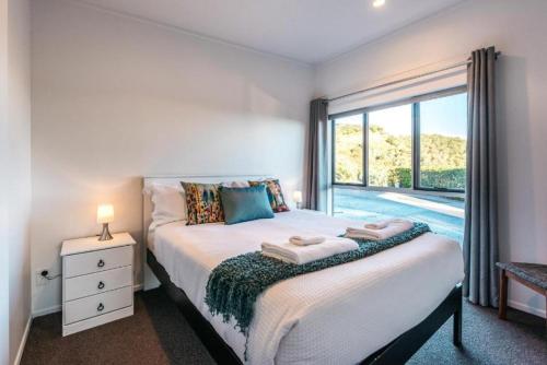 a bedroom with a bed and a large window at Delamore Cove - Kowhai - Waiheke Escapes in Matiatia Bay
