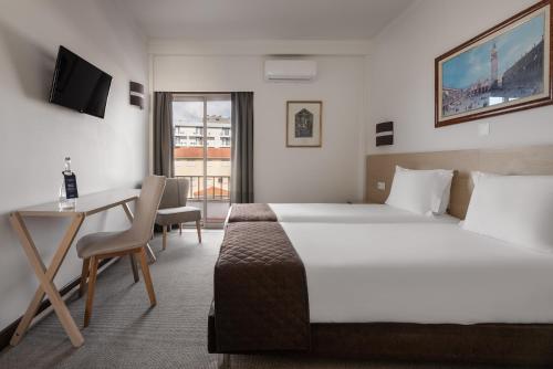 a hotel room with a large bed and a desk at Crisol Tres Pastorinhos in Fátima