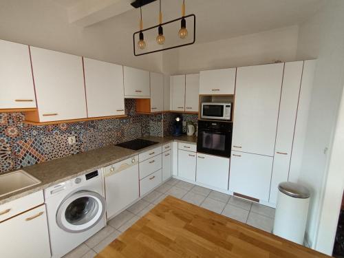 une cuisine avec des armoires blanches et une laveuse et une sécheuse dans l'établissement Logis le 18 rose, à Strasbourg