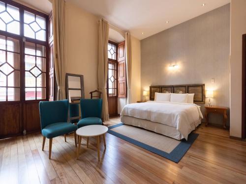 a bedroom with a bed and two chairs and a table at Casa El Edén in Quito