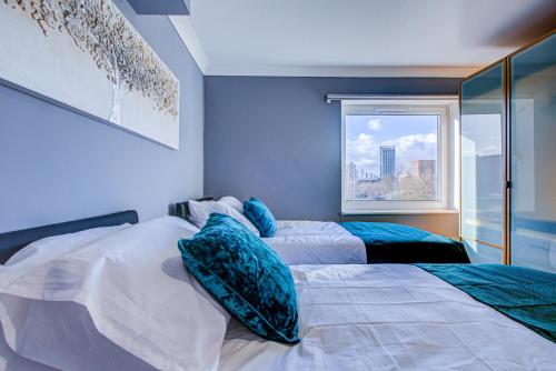 two beds in a room with a window at Statera Apartments - Thames View in London