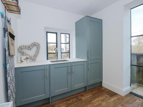 una cocina con armarios azules y una ventana en Kylemore Railway Cottage, en Stamford