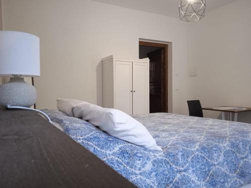 a bedroom with a bed with a blue blanket and a lamp at SOTTO LA ROCCA in Finale Ligure