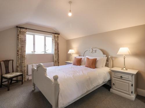 1 dormitorio con cama blanca y ventana en Kylemore Railway Cottage, en Stamford