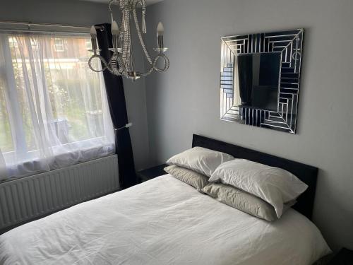 a bedroom with a bed with white sheets and a mirror at Lovely Stay in Parkside