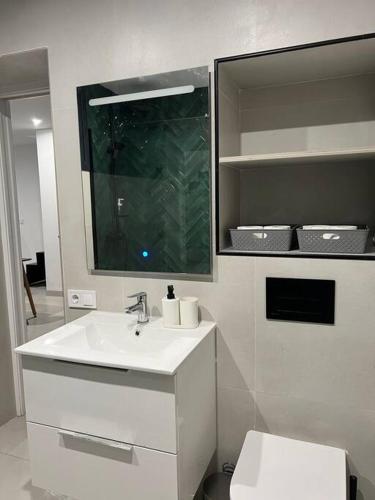 W łazience znajduje się umywalka, toaleta i lustro. w obiekcie Villa Zeus w mieście Rota