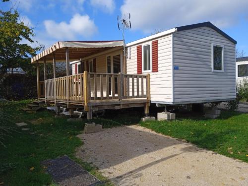 a tiny house with a porch and a deck at Joli mobil-home pour 8 personnes tout confort 3 chambres vue étang avec piscine in Onzain