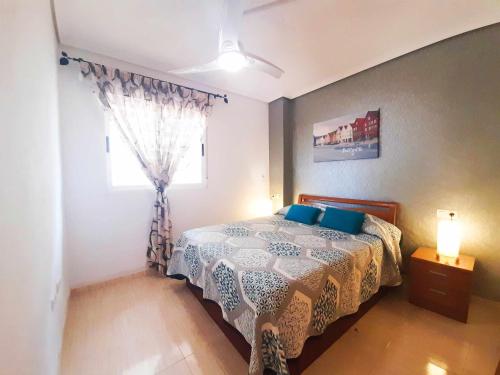 ein Schlafzimmer mit einem Bett mit blauen Kissen und einem Fenster in der Unterkunft Ayf 1ª linea de playa , costa marina dor in Oropesa del Mar