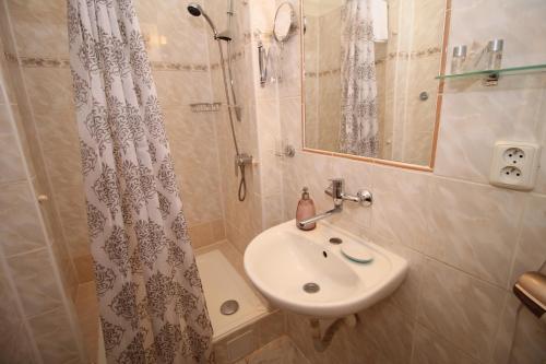 La salle de bains est pourvue d'un lavabo et d'une douche. dans l'établissement Delux Kolonada, à Karlovy Vary