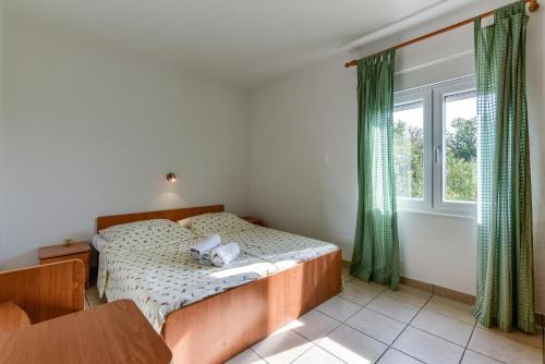 Schlafzimmer mit einem Bett mit grünen Vorhängen und einem Fenster in der Unterkunft Haus Manda - Wohnung 6 in Ražanac