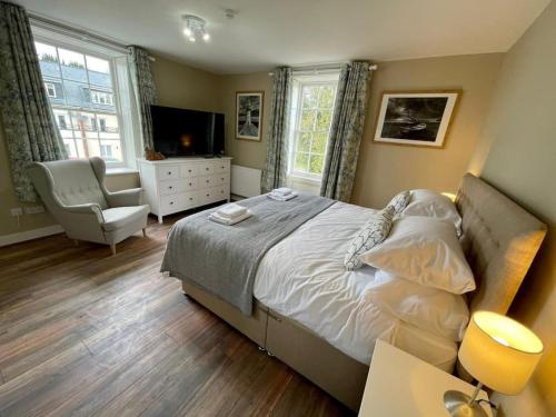 a bedroom with a bed and a television and a chair at Lydney House Swaffham Sleeps 22 in Swaffham