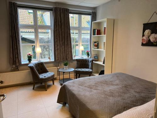 1 dormitorio con 1 cama, 2 sillas y ventanas en Apothekergaarden Stege stuen mod gårdhaven en Stege