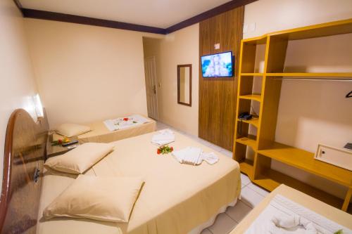 a room with two beds and a flat screen tv at Rede Andrade Terra Brasil in Porto Seguro