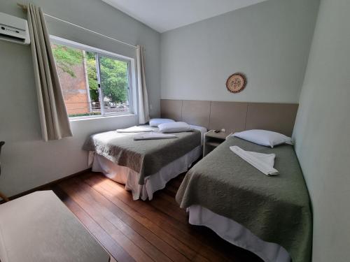 um quarto com duas camas e uma janela em Hotel Hermann em Blumenau