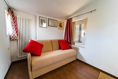 a living room with a couch and two red pillows at Appartamento Palazzo Barocci in Urbino