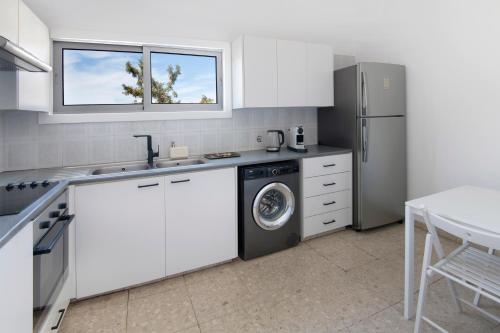 cocina con armarios blancos, lavadora y secadora en Urban Condo 12 - 2 Bdr en Nicosia