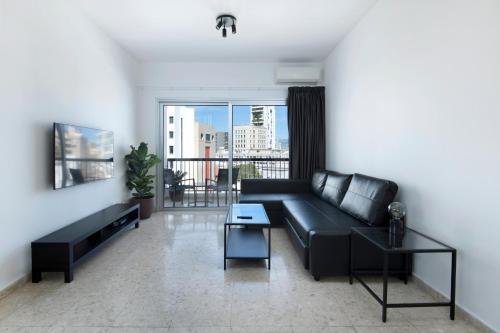 uma sala de estar com um sofá preto e uma varanda em Urban Condo 12 - 2 Bdr em Nicósia