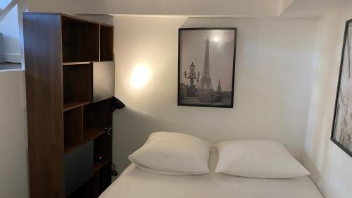 - une chambre avec un lit et une photo sur le mur dans l'établissement Marais joli deux pièces, à Paris