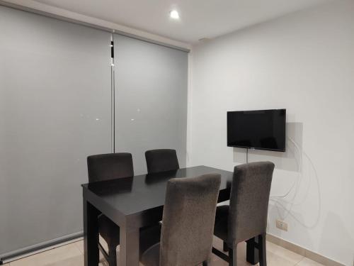 a dining room table with chairs and a tv on a wall at Enjoy Apart Campana in Campana