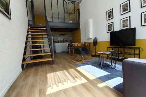 ein Wohnzimmer mit einer Treppe und einem TV in der Unterkunft La verrière sur cour #L6 in Grenoble