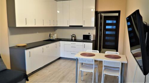 uma cozinha com armários brancos e uma mesa e cadeiras em Jedenastka em Plock