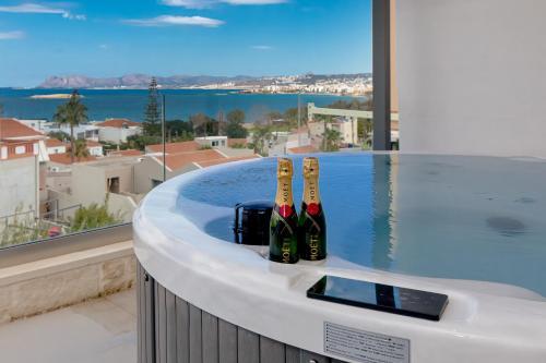 3 botellas de vino sentadas en una bañera con piscina en Perla Dream Luxury Villa en La Canea