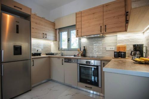 a kitchen with wooden cabinets and stainless steel appliances at Μοντέρνο διαμέρισμα ALMYRA in Agios Nikolaos