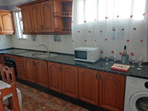 eine Küche mit einer Theke mit einer Mikrowelle und Weingläsern in der Unterkunft piso villavarela in Tarifa