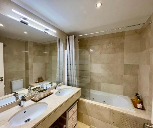 a bathroom with two sinks and a bath tub at Casares Beach Golf Apartment With Private Garden Direct Pool Access in Casares