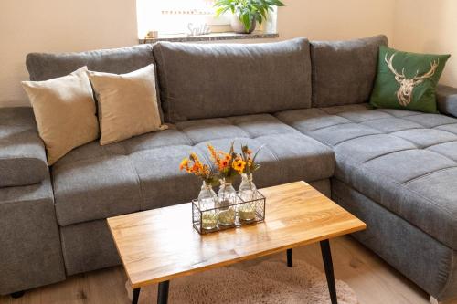 a living room with a gray couch and a wooden table at Rhön & Relax Schwarze Berge - Garten in Wildflecken