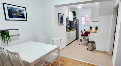 a kitchen and dining room with a white table and chairs at Eilat Octopus Apartment - אילת אוקטופוס -שני חדרים וסלון, בריכה בקיץ in Eilat
