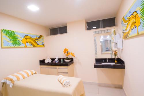 a bathroom with a bed and a sink in a room at Portal Ville - Rede Soberano in Porto Seguro
