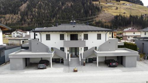 a large white house with cars parked in front of it at Golf & Ski Appartements Mittersill Trausmuth Monika inkl Sommercard - Golfplatz 500 m entfernt, inkl Waschmaschine, Trockner in Mittersill