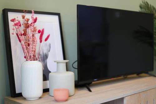 Deux vases blancs et une télévision sur une table dans l'établissement Loios Studios and Apartments, à Lisbonne