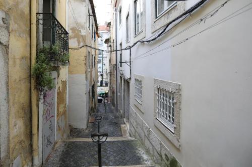 Une ruelle étroite avec des bâtiments et une table au milieu dans l'établissement Loios Studios and Apartments, à Lisbonne