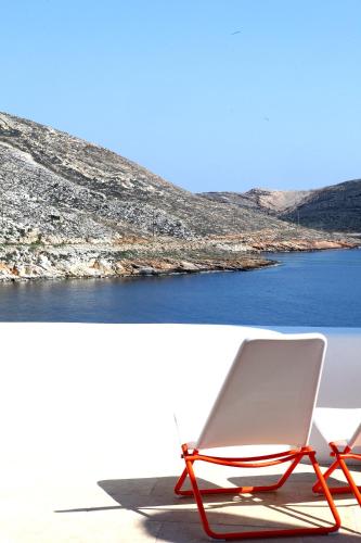 a white chair sitting on a beach next to the water at PANORMOS ART Beachfront Suites in Panormos
