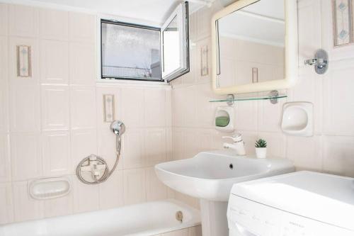 La salle de bains blanche est pourvue d'un lavabo et d'un miroir. dans l'établissement Apartment in Athens, Pagrati, à Athènes