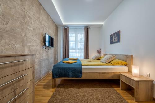 - une chambre avec un lit doté d'oreillers jaunes et une télévision dans l'établissement Apartman Montis Zlatibor, à Zlatibor