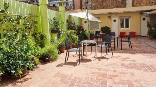 un patio con mesa, sillas y plantas en Paraiso Hostel, en Barcelona