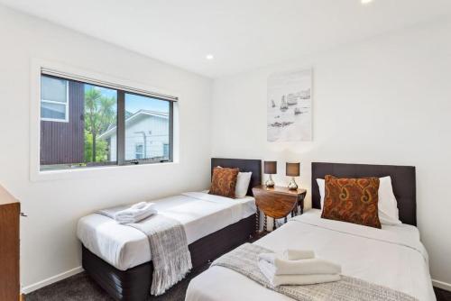 um quarto com 2 camas e uma janela em Cascade Cottage with Parking and Wi-Fi em Auckland
