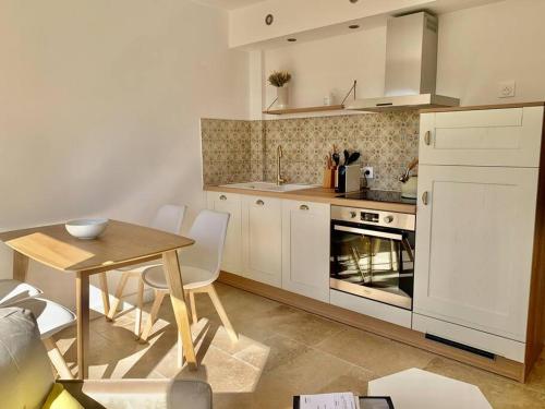 une cuisine avec des placards blancs, une table et une salle à manger dans l'établissement La Reposée, bas de villa en plein cœur de Vence, à Vence