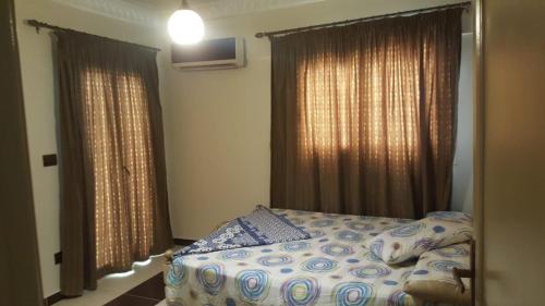 a bedroom with a bed and two windows with curtains at ستانلي اسكندريه in Alexandria