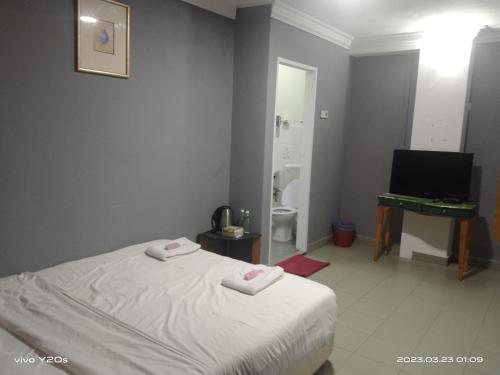 a bedroom with a bed and a television and a bathroom at BASE HOTEL in Kuala Kubu Bharu